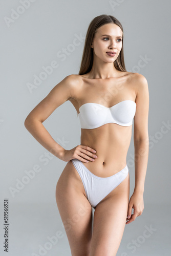 Young pretty woman with perfect slim body. Beautiful woman wearing inner wear, smiling and posing on grey background.