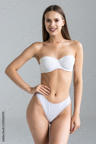 Proud of her perfect body. Attractive young brown hair woman in white lingerie posing against grey background © F8  \ Suport Ukraine