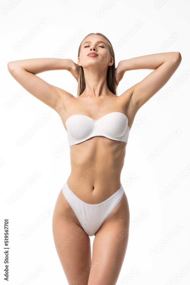 Smiling sporty woman in white underwear posing on studio background. Female beauty, sport, spa concept Smiling sporty woman in white underwear posing on studio background. Female beauty, sport, spa concept
