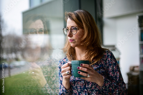 Woman drinking coffee and looking out the window in room
