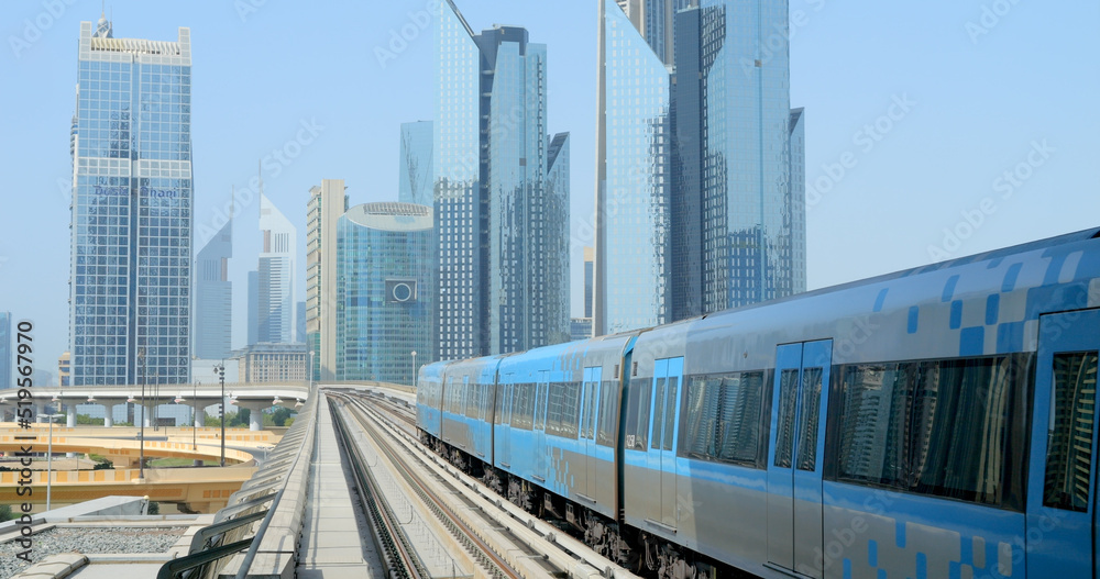 Naklejka premium Dubai, OAE, July 23, 2022 - the subway train rides on skyscrapers background