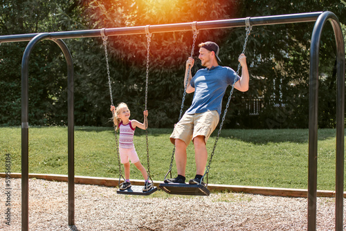 Father and daughter in the park having fun on swing