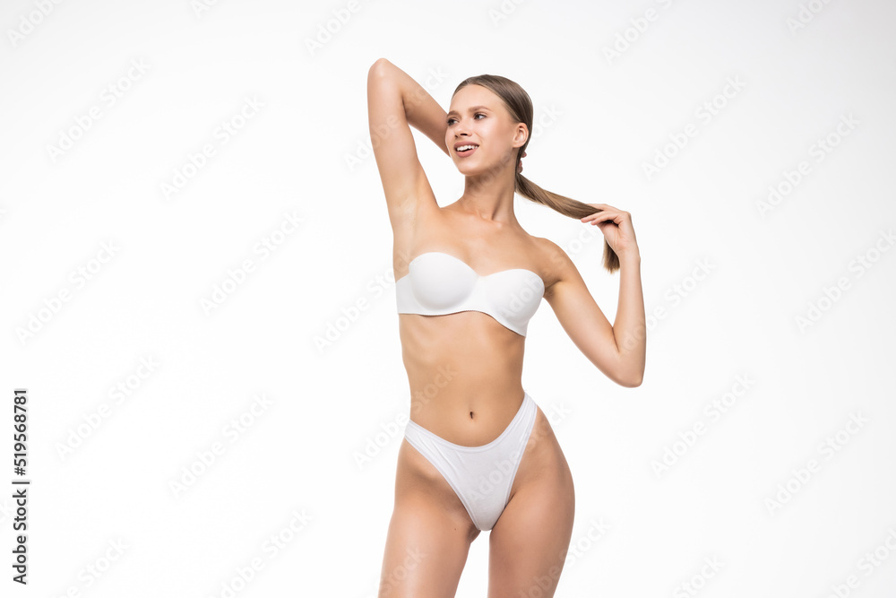 Smiling sporty woman in white underwear posing on studio background with copy space. Female beauty, sport, spa concept Smiling sporty woman in white underwear posing on studio background with copy space. Female beauty, sport, spa concept