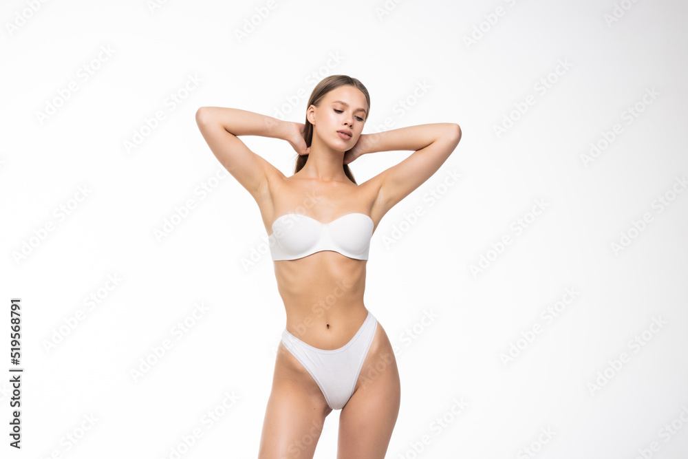 Smiling sporty woman in white underwear posing on studio background with copy space. Female beauty, sport, spa concept Smiling sporty woman in white underwear posing on studio background with copy space. Female beauty, sport, spa concept