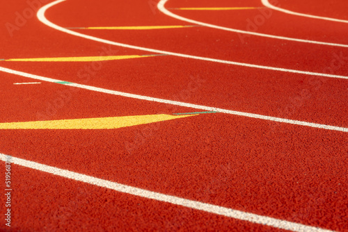 Inspiring close up of the start of an exchange zone on a new red running track with white lane lines and other markings. 