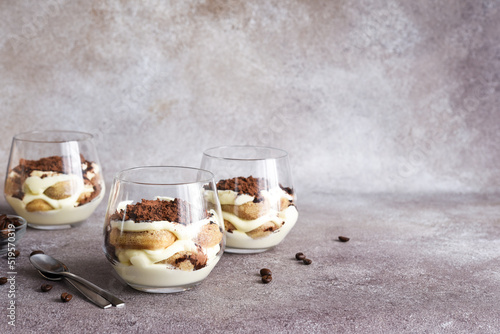 Classic tiramisu with savoiardi in a glass on a brown stone background