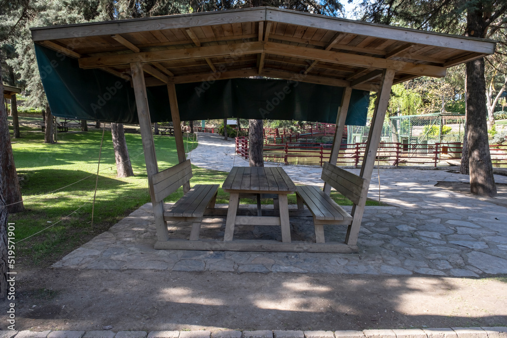 Picnic shelter or Covered picnic table in public park.  Wooden eating bench.