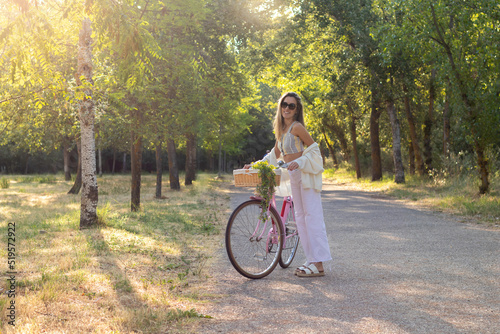 Young blonde woman looking to camera while riding a bicycle in the middle of the natural enviroment