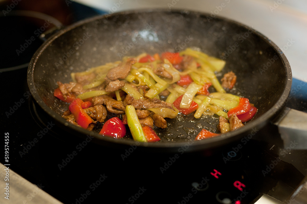 Cook fries meat in a pan with vegetables. Cook fries meat in a pan with vegetables.