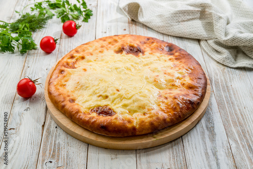 Ossetian pie with cheese on white wooden table