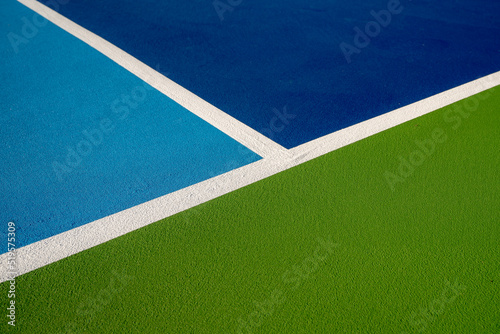 Example image of a newly surfaced, empty pickleball court with multi-color surface and white lines. 