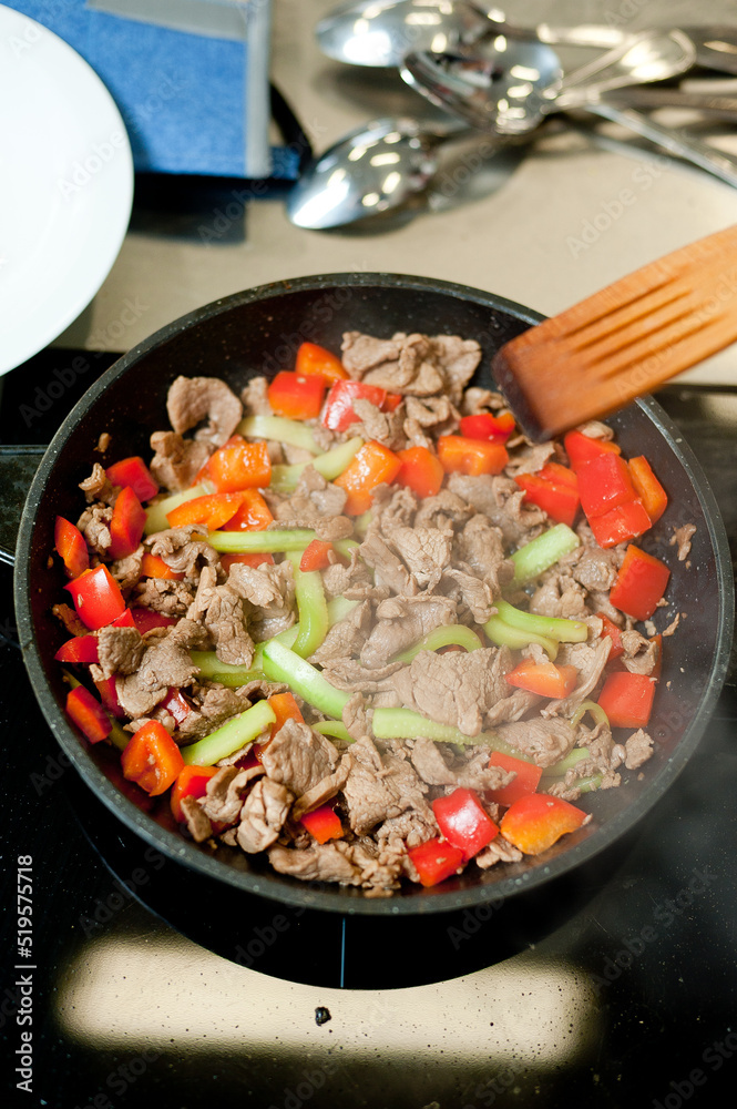 Cook fries meat in a pan with vegetables. Cook fries meat in a pan with vegetables.