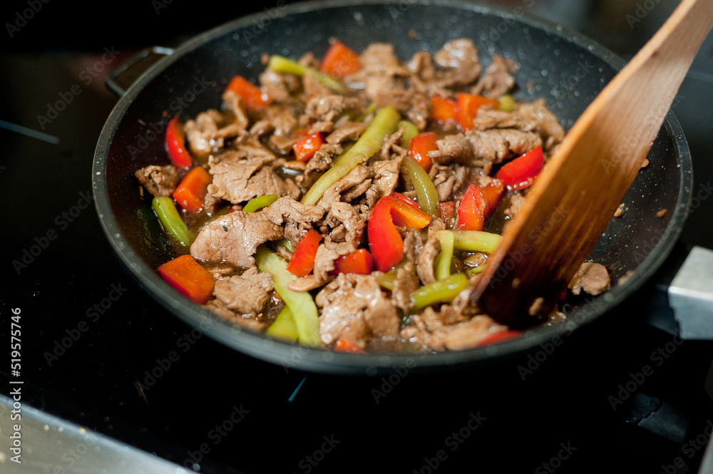 Cook fries meat in a pan with vegetables. Cook fries meat in a pan with vegetables.