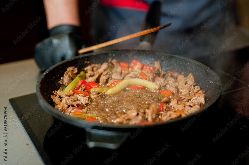 Cook fries meat in a pan with vegetables. Cook fries meat in a pan with vegetables.