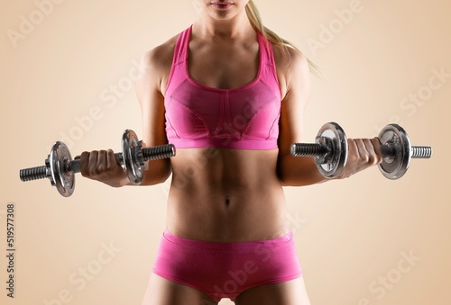 Sporty woman exercises with dumbbells. Good shape and health fitness woman weight training standing pose smile to camera.