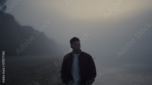 Sad man walking sea shore. Upset guy feeling lonely. Model looking foggy ocean