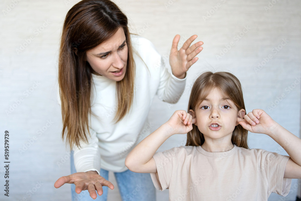 Daughter closing ears while mother scolding her. Daughter closing ears while mother scolding her.