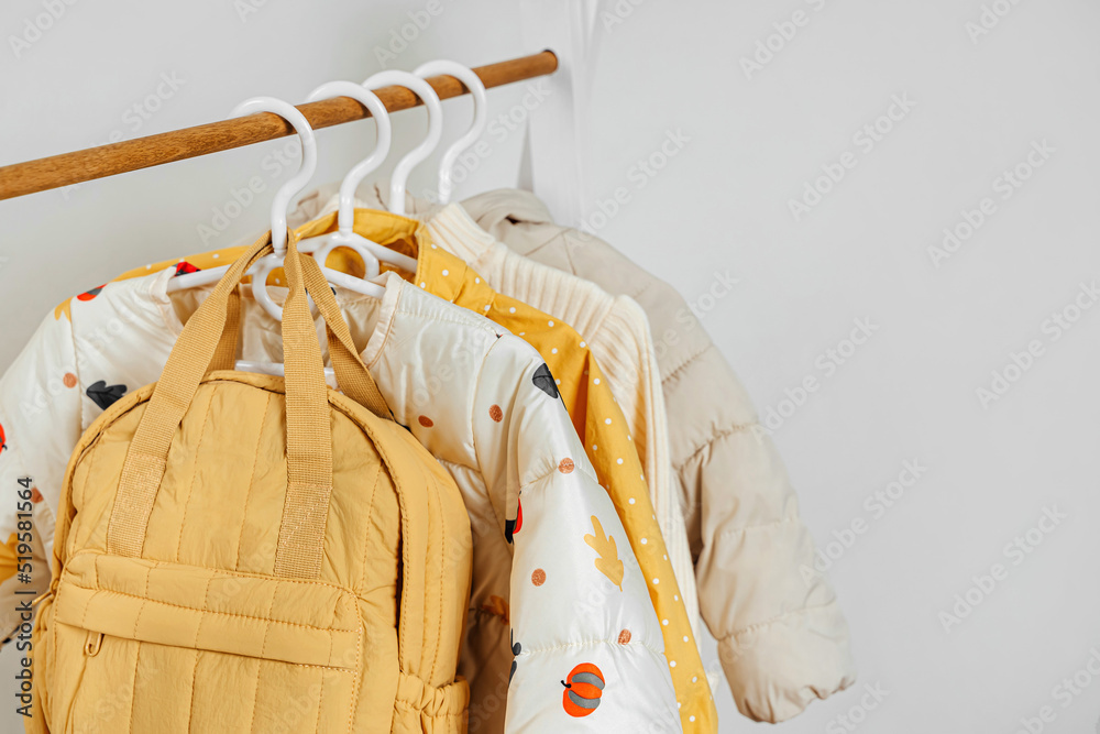 Wooden Clothing Rack with children's autumn outfit. Yellow backpack