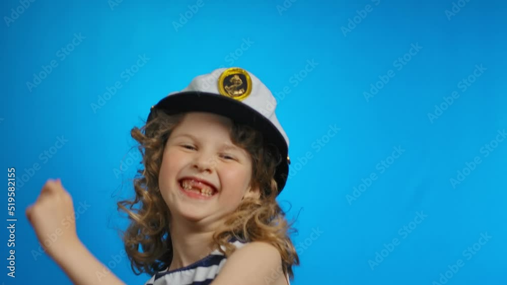 A little curly sailor girl is dancing and smiling cheerfully in the studio A little curly sailor girl is dancing and smiling cheerfully in the studio
