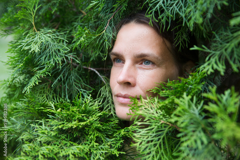 Profile of a enjoying nature middle aged woman to stand in thuja branches breathing fresh air. celebrate earth's day. Aromatherapy and Spa concept. ecology. climate change Profile of a enjoying nature middle aged woman to stand in thuja branches breathing fresh air. celebrate earth's day. Aromatherapy and Spa concept. ecology. climate change