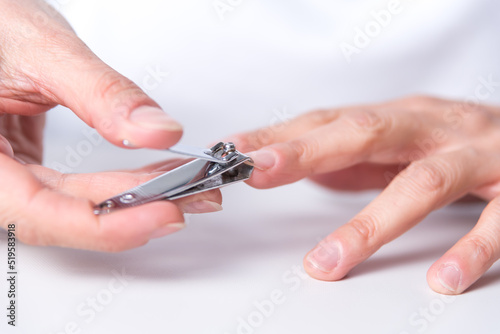 close up of adult woman's hands, cutting a nail, manicure at home, hand care, beauty and body health at home, nail clippers