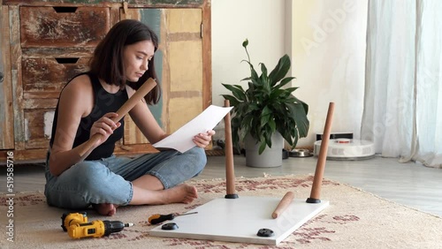 Caucasian beautiful young woman assembles furniture according to instructions. home improvement concept. 4k footage