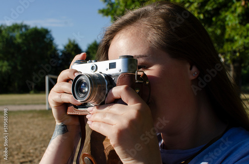 Young woman taking picture with an old/vintage film camera	 photo