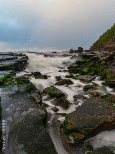 Water flowing between rock formation on the shore.