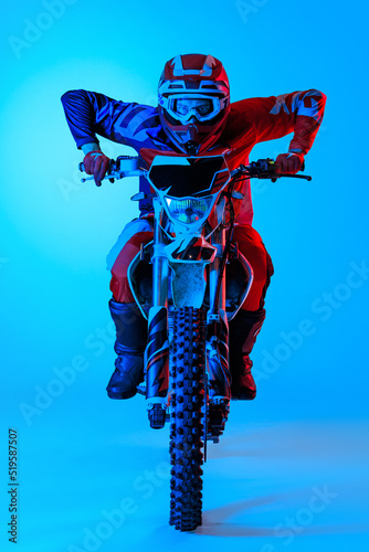 Canvas Print Portrait of young concentrated man, biker developing speed on motorbike isolated