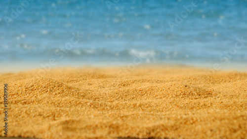 The brown sandy beach is focus on point with a blurry sea background. Summer vacations, vacation breaks travel relaxation, placement spaces for texts and advertisements.