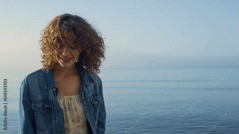 Fashionable girl posing at seashore. Smiling woman turning around on ocean beach