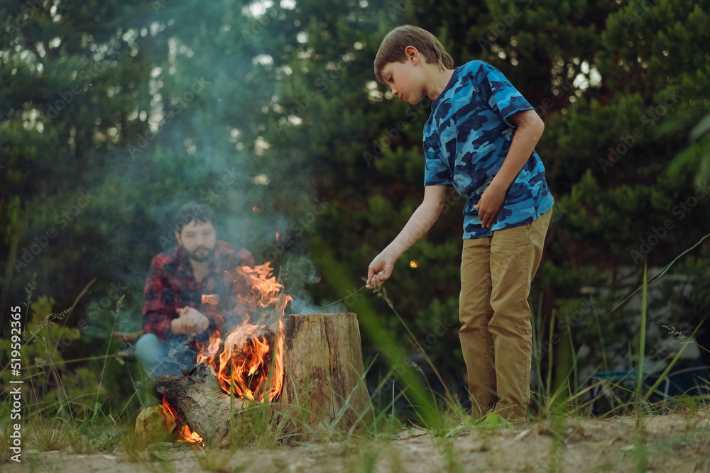 Father and son sitting by fireplace. Camping concept. Image with selective focus Father and son sitting by fireplace. Camping concept. Image with selective focus