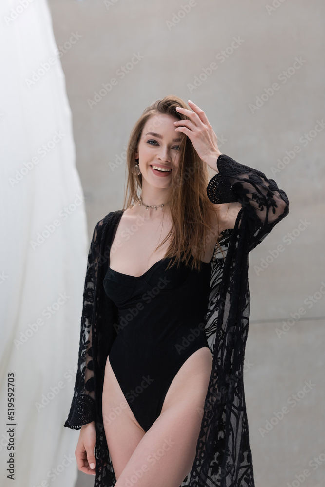 Fototapeta premium Positive woman in stylish swimsuit looking at camera at resort.