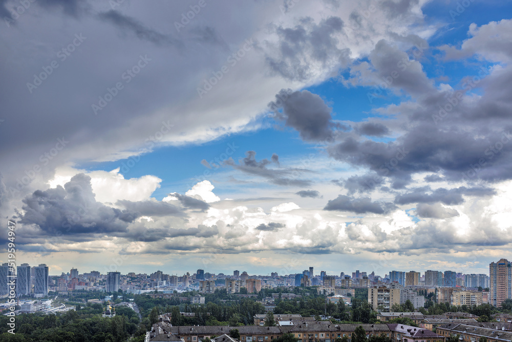 Thunderclouds fill the blue sky above the city.
