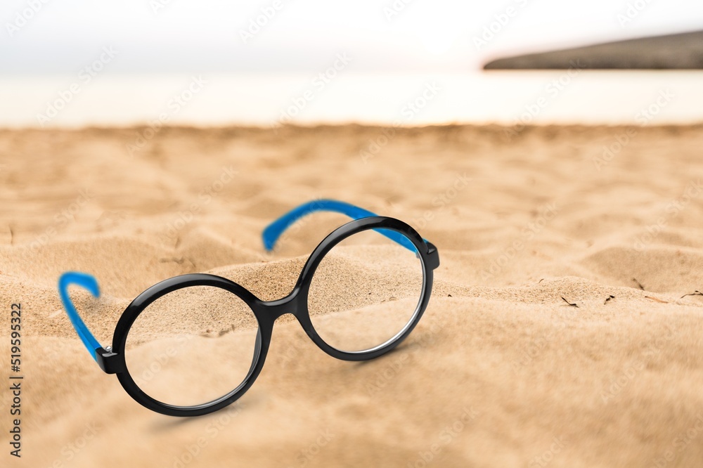 Trendy glasses in plastic frame on beach. Optic store discount. Eyewear fasion promotion. Trendy glasses in plastic frame on beach. Optic store discount. Eyewear fasion promotion.