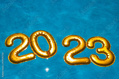 figures 2023 new year float in the blue pool in splashes of water