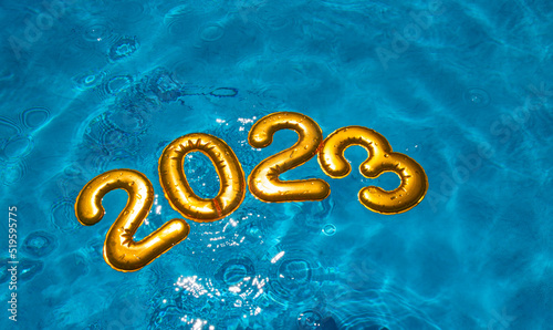 figures 2023 new year float in the blue pool in splashes of water