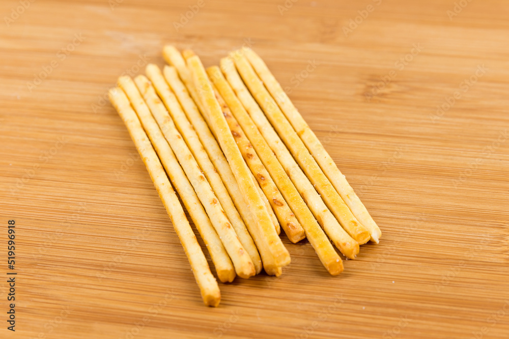 Yellow corn snack sticks side view on a wood cutting board