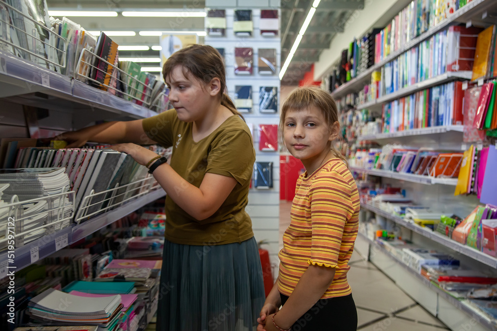 Smiling teenagers choosing different  copybook in stationery store