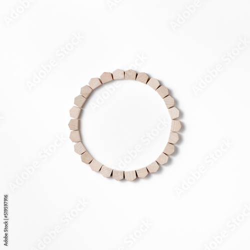 Composition of wooden figures of houses assembled in a ring with a void in the center in a flat lay. Concept to illustrate the purchase or sale of real estate. Top view with copy space.