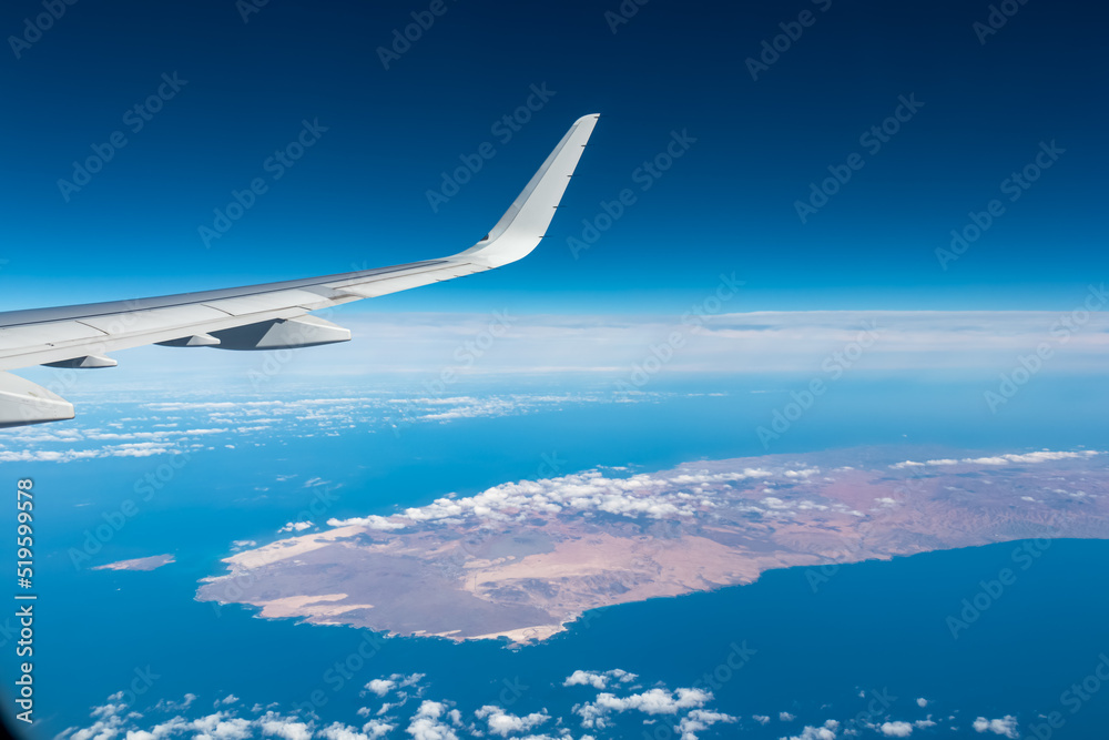 Aerial window view from an airplane on Fuerteventura, Canary Islands, Spain, Europe, EU. Wing and turbines of the aircraft can be seen. Flying high above the ground. Freedom. Flying into vacation Aerial window view from an airplane on Fuerteventura, Canary Islands, Spain, Europe, EU. Wing and turbines of the aircraft can be seen. Flying high above the ground. Freedom. Flying into vacation