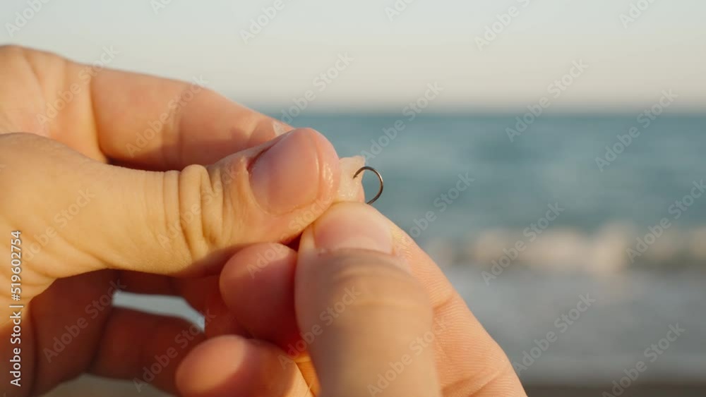 A man puts a piece of chicken on a hook, fishing at sea. slow motion. Sea and waves in the background.