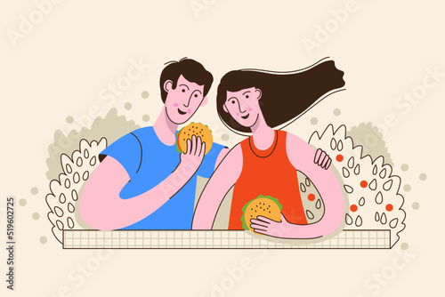 Happy young couple spending time together, resting in nature, eating burgers. Summer vacation