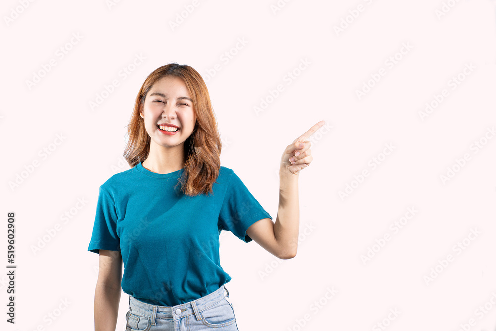 A graceful Asian woman smiles happily and points to a separate empty space on a white background. A graceful Asian woman smiles happily and points to a separate empty space on a white background.