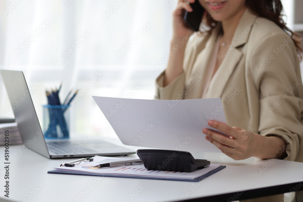 Businesswoman talking on the phone, she is a salesperson in a company, she is calling customers to sell products and promotions. Woman talking on the phone and reading work schedule.