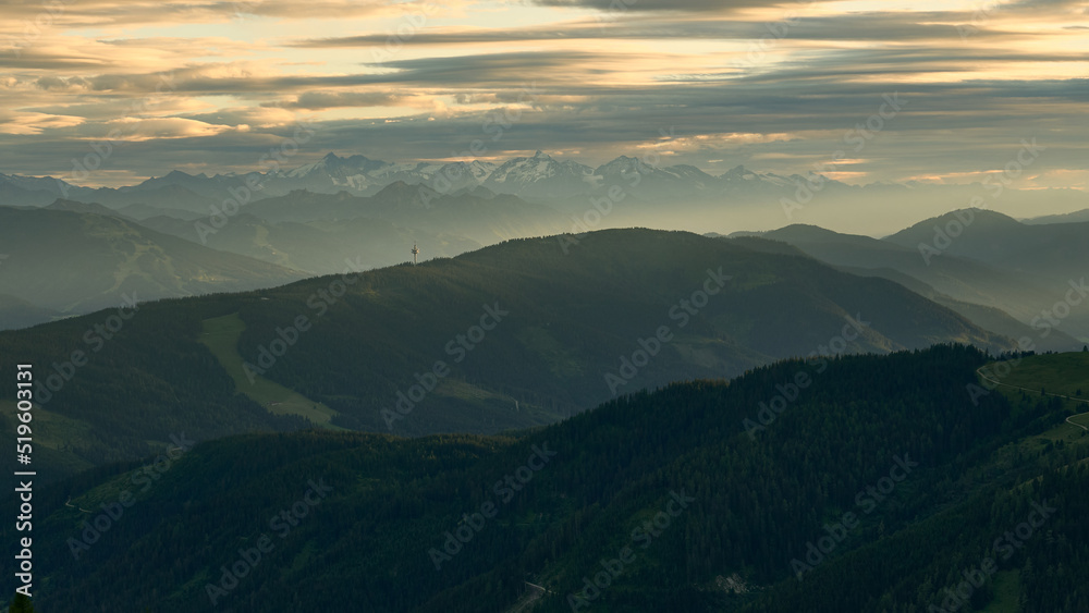 layers upon layers of rolling hills and distant mountains as seen from Südwandhütte in the Dachstein region of the austiran alps in summer, central alps in the hazy distance