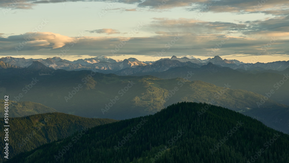 dreamy landscape with the moutians of the central alps in the distance and hazy sunset in the austrian alps near Dachstein