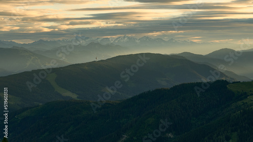 layers upon layers of rolling hills and distant mountains as seen from Südwandhütte in the Dachstein region of the austiran alps in summer, central alps in the hazy distance