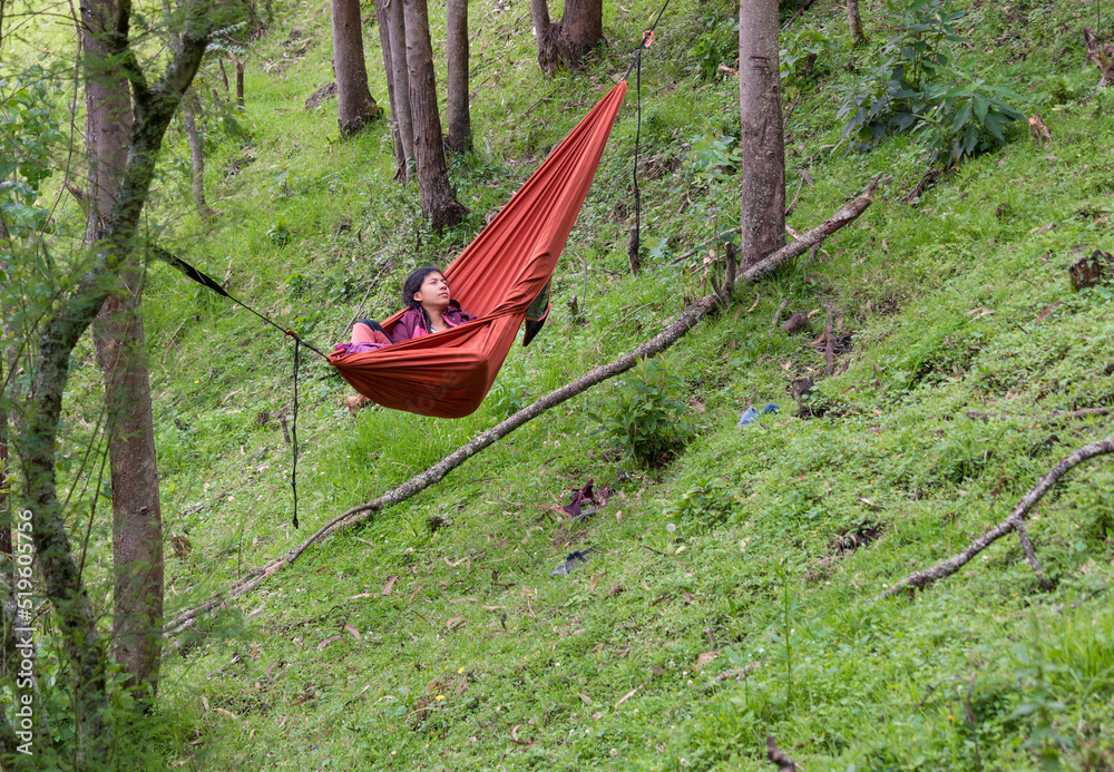 Bipoc woman relaxing in a hammock in the woods