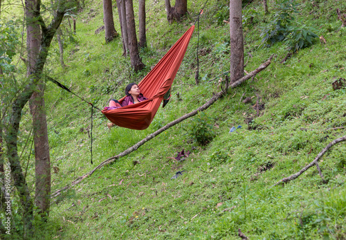 Bipoc woman relaxing in a hammock in the woods